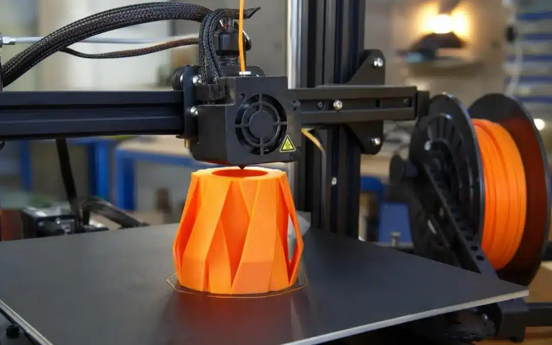 Impression 3D définition: pièce orange imprimée en forme géométrique complexe sur la plaque de construction d’une imprimante 3D.